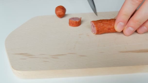 Female hands cut slice hunting sausage on wooden kitchen board with a black ceramic knife — Stock Video