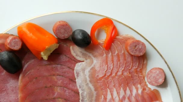 Meat and sausage slices on plate next to black olives, paprika with cheese and hunting sausages. Salami and sliced ham. Arranged dried meat in restaurant. Appetizing. Cured meat plate — Stock Video