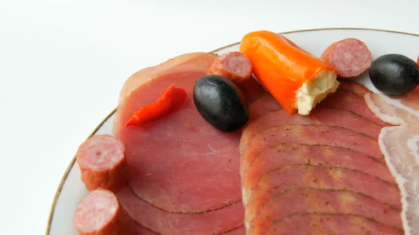 Viande et tranches de saucisse dans une assiette à côté des olives noires, paprika au fromage et saucisses de chasse. Salami et jambon tranché. Viande séchée arrangée au restaurant. C'est appétissant. Assiette de viande séchée — Video