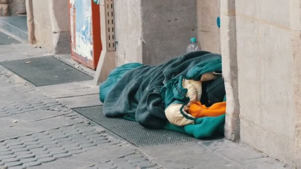 Нюрнберг, Германия - 10 декабря 2019 года: бездомный бедный нищий лежит на земле в спальном мешке и просит милостыню на городской улице зимой — стоковое видео
