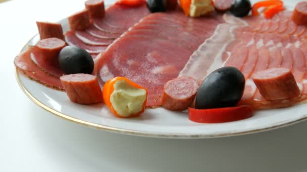 Fleisch- und Wurstscheiben auf dem Teller neben schwarzen Oliven, Paprika mit Käse und Jagdwurst. Salami und Schinken in Scheiben. arrangierte Trockenfleisch im Restaurant. Appetitlich. gepökelte Fleischplatte — Stockvideo