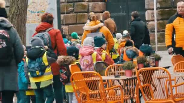 Nürnberg, Tyskland - 10 december 2019: En grupp små barn i förskoleåldern i reflekterande västar går på utflykter i rad med barnsköterskorna på gatorna. — Stockvideo
