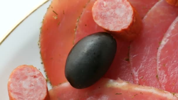 Meat and sausage slices on plate next to black olives, paprika with cheese and hunting sausages. Salami and sliced ham. Arranged dried meat in restaurant. Appetizing. Cured meat plate — 비디오