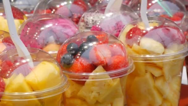 Counter with tropical fruits, mangoes, passion fruit, kiwi, bananas, strawberry in plastic packaging. Healthy fresh diet food ready to eat, assorted cut fruit in plastic glasses for sale. — 비디오