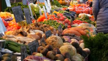 Çok çeşitli meyveleri olan sebze ve meyve pazarı. Sağlıklı vejetaryen yemekleri. Büyük şehirde sebze pazarı. Tezgahta sağlıklı taze organik vegan yiyecekler var. Fiyat etiketleri Almanca.