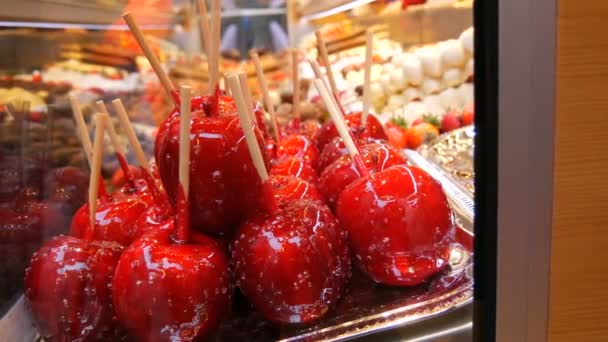 Berbagai buah pada tusuk sate kayu dalam glasir karamelisasi yang terbuat dari susu cokelat putih hitam. Apel dalam lapisan es di meja pasar Natal. Jalan makanan — Stok Video