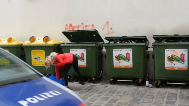 Bécs, Ausztria - 2019. december 19.: Üres üvegeket dob a nő. Színes üvegpalackok műanyag szemeteskonténerei. Szemetet válogatok és újrahasznosítok. Felirat német nyelven — Stock videók