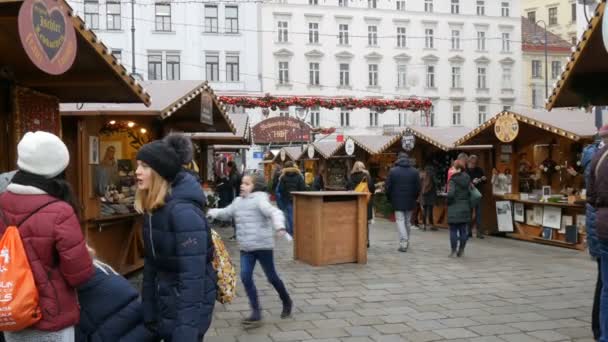 ウィーン,オーストリア- 2019年12月19日:伝統的なヨーロッパのクリスマスマーケット。昼間に通り過ぎる様々なお土産や食べ物を持つキオスク — ストック動画