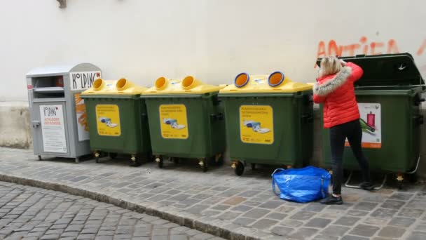 Wiedeń, Austria - 19 grudnia 2019: Kobieta rzuca pustymi butelkami. Plastikowe pojemniki na śmieci do kolorowych szklanych butelek. Sortowanie i recykling śmieci. Napis w języku niemieckim — Wideo stockowe