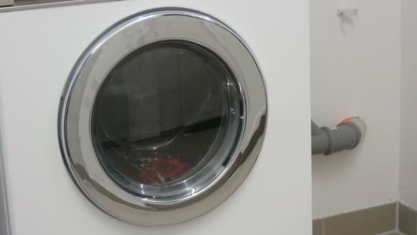 Svartvita kläder. Tvätt tvättas i en vit tvättmaskin i tvätten. — Stockvideo