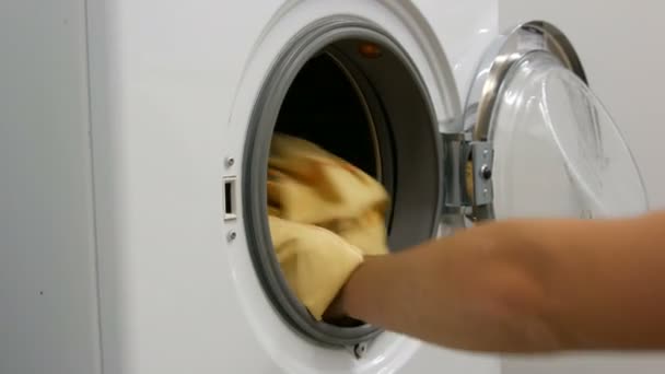 Mannelijke handen laden het wassen van gekleurde was in de wasmachine en plaats de capsule met waspoeder — Stockvideo