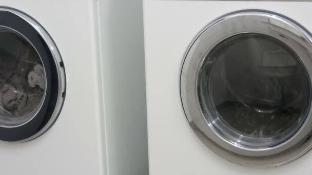 Fekete-fehér ruhák. A mosást fehér mosógépben mossák a mosodában.. — Stock videók