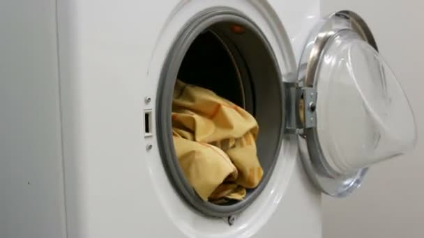 Τα αρσενικά χέρια φορτώνουν ένα πλύσιμο των χρωματιστών ρούχων σε ένα πλυντήριο ρούχων και τοποθετούν μια κάψουλα με σκόνη πλυσίματος. Ταχεία βολή — Αρχείο Βίντεο