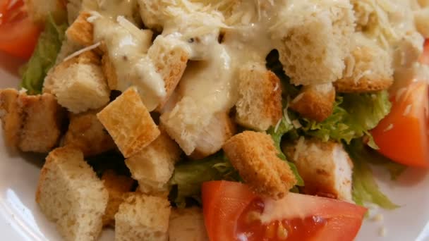 Smaczna zdrowa sałatka Cezar z serem parmezan, krakersy, pomidor, mięso z kurczaka, i sałata na talerzu w restauracji — Wideo stockowe