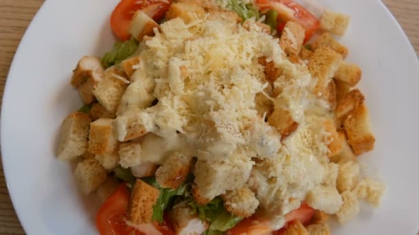 Tasty healthy fresh Caesar salad with parmesan cheese, crackers, tomato, chicken meat, and lettuce on plate in restaurant — Stock Video