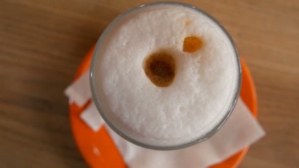 Lahodné čerstvě uvařené latté na stole v kavárně. Latté kávová mléčná pěna v průhledné dlouhé speciální sklenici. Horní pohled — Stock video