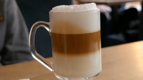 Leckerer frisch zubereiteter Latte auf einem Tisch in einem Café. Latte-Kaffee-Milchschaum in einem transparenten langen Spezialglas. — Stockvideo