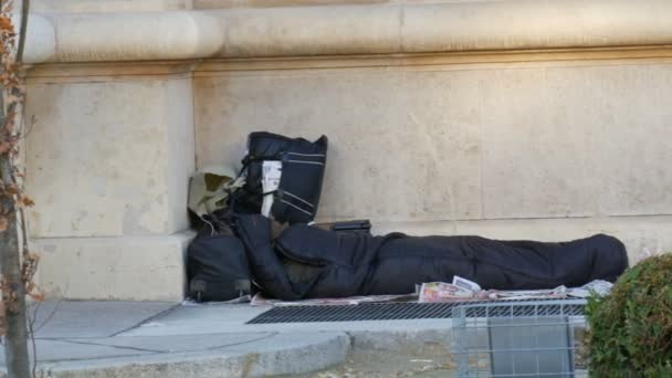 Wien, Österreich - 20. Dezember 2019: Obdachloser liegt in Schlafsack unter dem Gebäude. — Stockvideo