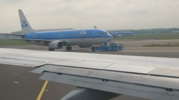 Amsterdam, Paesi Bassi - 26 aprile 2019: Aeroporto di Schiphol, uno dei più grandi al mondo. Un aereo è in fase di preparazione per il decollo, guidando oltre l'aereo che si trova e che decolla — Video Stock