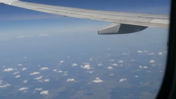 El avión vuela sobre las raras nubes esponjosas. Campos de Europa vista desde el ojo de buey en el ala del avión — Vídeos de Stock