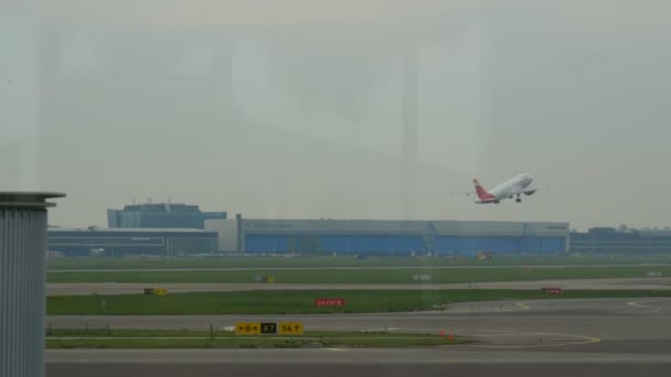 Amsterdam, Holandia - 25 kwietnia 2019: Widok z okna terminala na pas startowy, na którym startuje samolot, Międzynarodowy Port Lotniczy Schiphol — Wideo stockowe