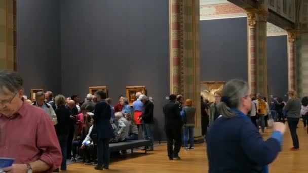 Amsterdam, 25 april 2019: Mensen maken foto 's op de mobiele telefoon en kijken naar beroemde foto' s in het Rijksmuseum. Publieke toerist geïnteresseerd in kunst. — Stockvideo