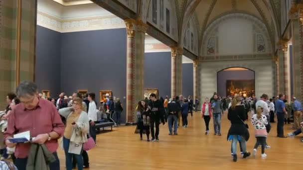 AMSTERDAM, PAÍSES BAJOS - 25 de abril de 2019: La gente toma fotos en el teléfono móvil y ve fotos famosas, en el Rijksmuseum. Multitud de turistas interesados en el arte . — Vídeos de Stock