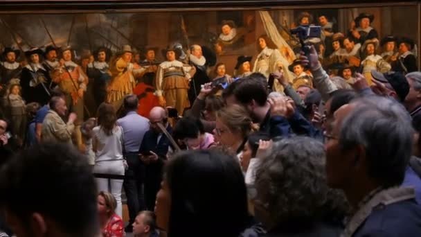 AMSTERDAM, NETHERLANDS - 25 April 2019: Orang-orang mengambil gambar di ponsel dan menonton gambar The Night Watch of Rembrandt, di Rijksmuseum. Rombongan turis tertarik pada seni. . — Stok Video