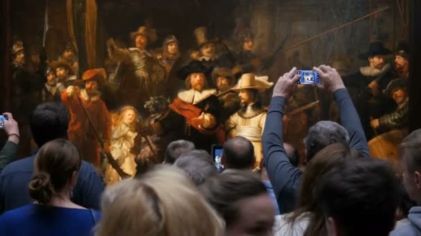 AMSTERDAM, NETHERLANDS - 25 April, 2019: People take pictures on the mobile phone and watching picture The Night Watch of Rembrandt, in Rijksmuseum. Crowd tourist interested in art. — Stock Video