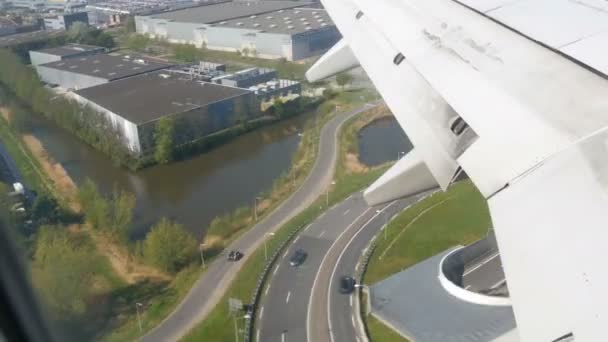 飛行機は着陸の準備をしている。水路、温室、ソーラーパネル付き農場、家、アムステルダム、オランダ、オランダの都市のルートの上を飛ぶ — ストック動画