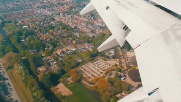 Het vliegtuig bereidt zich voor op de landing. Vliegen over water kanalen, kassen, boerderijen met zonnepanelen, huizen, de route van de stad Amsterdam, Nederland, Nederland — Stockvideo