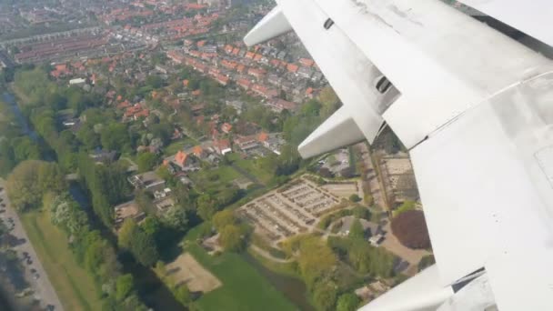 O avião está a preparar-se para aterrar. Voando sobre canais de água, estufas, fazendas com painéis solares, casas, a rota da cidade de Amsterdã, Holanda, Países Baixos — Vídeo de Stock