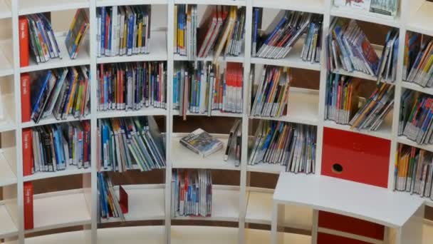 Amsterdam, Holandia - 24 kwietnia 2019: Modne stylowe wnętrze w nowoczesnej bibliotece publicznej. Białe regały i półki w nowym budynku — Wideo stockowe