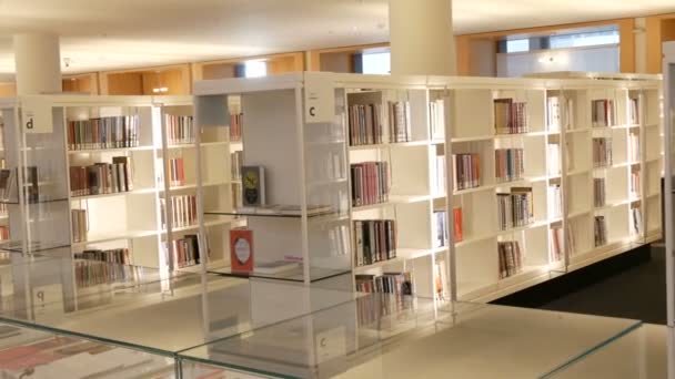 Amsterdã, Holanda - 24 de abril de 2019: Prateleiras novas brancas modernas com estantes com vários livros em biblioteca pública — Vídeo de Stock