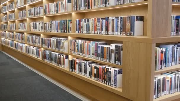 アムステルダム,オランダ- 2019年4月24日:公共図書館にさまざまな本がある本棚付きのモダンな新しい棚 — ストック動画