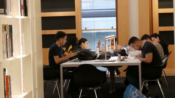 Amsterdam, Pays-Bas - 24 avril 2019 : Les lecteurs apprécient l'environnement apaisant, bâtiment au design unique. Une entreprise de jeunes étudiants s'assoit et étudie à table dans une bibliothèque publique — Video