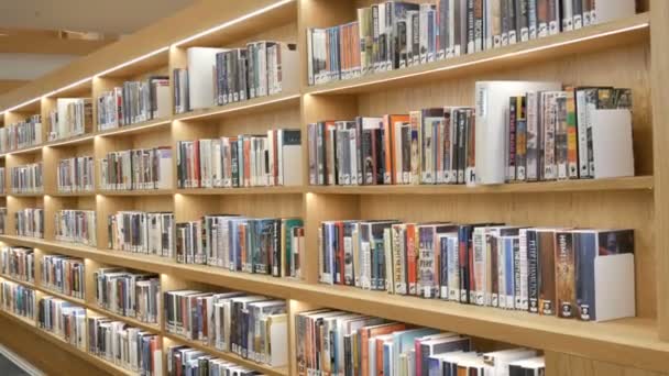 Amsterdam, Nizozemsko - 24. dubna 2019: Moderní nová police s knihovnami s různými knihami ve veřejné knihovně — Stock video