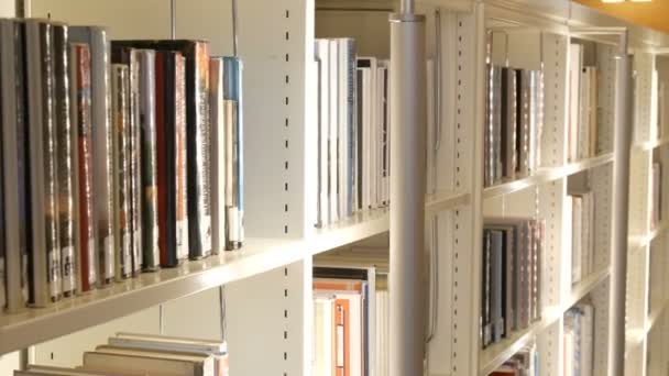 Amsterdam, Alankomaat - huhtikuu 24, 2019: Moderni valkoinen uusi hyllyt kirjahyllyt eri kirjoja julkisessa kirjastossa — kuvapankkivideo