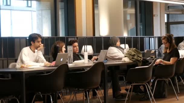 Ámsterdam, Países Bajos - 24 de abril de 2019: Los lectores disfrutan del ambiente tranquilo, construyendo con un diseño único. Una compañía de jóvenes estudiantes se sienta y estudia en una biblioteca pública — Vídeos de Stock