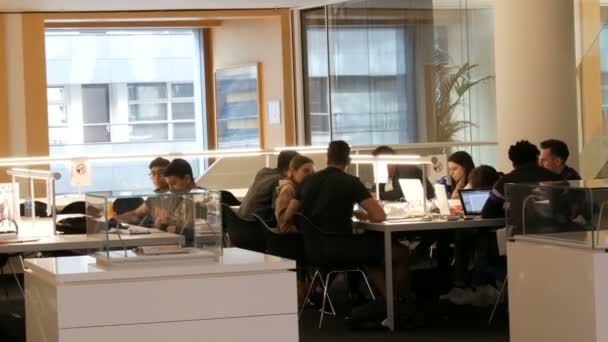 Amsterdã, Holanda - 24 de abril de 2019: Leitores desfrutando do ambiente calmante, edifício com design único. Uma empresa de jovens estudantes se senta e estuda à mesa em uma biblioteca pública — Vídeo de Stock