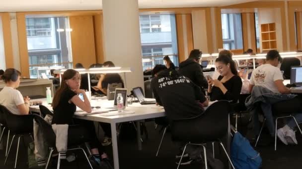 Άμστερνταμ, Ολλανδία - 24 Απριλίου 2019: Αναγνώστες απολαμβάνουν το ήρεμο περιβάλλον, χτίζοντας με μοναδικό σχεδιασμό. Μια εταιρεία νέων φοιτητών κάθεται και σπουδάζει στο τραπέζι σε μια δημόσια βιβλιοθήκη — Αρχείο Βίντεο