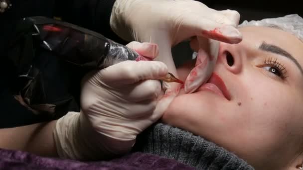 Мікроблокування татуювання губ спеціальним забарвленням червоного пігменту, який виправляє колір губ у клініці косметології. Перманентна процедура макіяжу губ нанесення пігментного макіяжу на губи за допомогою татуювальної машини — стокове відео