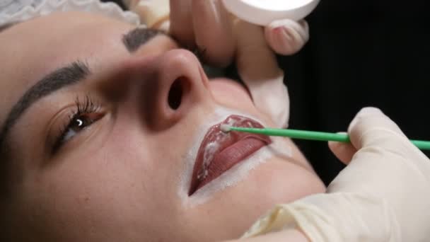 Schoonheidsspecialiste meester brengt speciale verdoving aan op de lippen. Voorbereiding voor permanente lipmake-up. Moderne gezicht tatoeage — Stockvideo