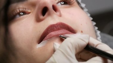 Mikroplu patinaj, mikro pigmentasyon dudaklar güzellik salonunda çalışır. Dudakları çizilmiş ve kalemle boyanmış bir kadın, yarı kalıcı makyaja hazırlanıyor.