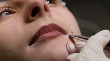 Mikroplu patinaj, mikro pigmentasyon dudaklar güzellik salonunda çalışır. Dudakları çizilmiş ve kalemle boyanmış bir kadın, yarı kalıcı makyaja hazırlanıyor.
