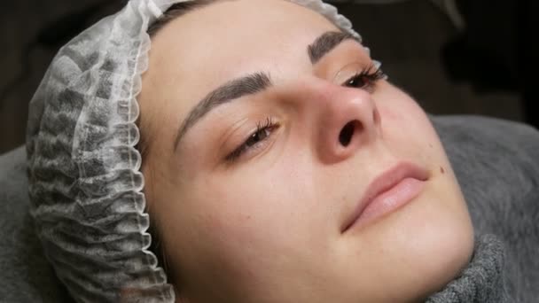 Preparation for permanent lip make-up. The face of a young girl in a special hat and real, not tattooed lips — Stock Video
