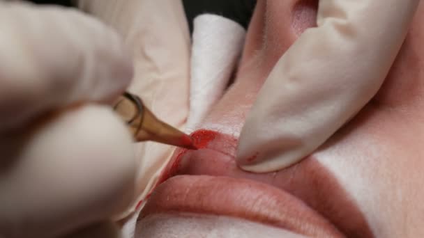 Tatuaje de labio Microblading con un pigmento rojo colorante especial que corrige el color de los labios en una clínica de cosmetología. Procedimiento permanente de los labios del maquillaje que aplica el maquillaje del pigmento en labios con una máquina del tatuaje — Vídeos de Stock