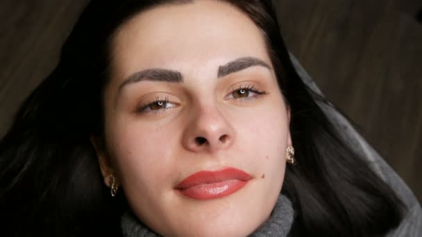 Face of a young beautiful girl. Final result of permanent lip makeup. Girl light red lips close up — Stockvideo