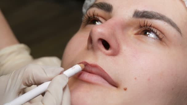 Мікроблокування, мікропігментація губ працює в салоні краси. Жінка, маючи губи намальовані і тоновані олівцем, готується до напівпостійного макіяжу — стокове відео
