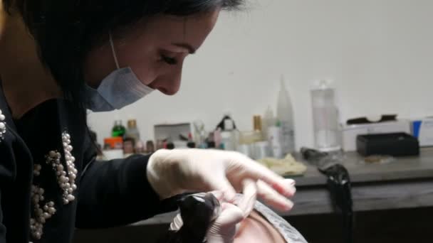 Beautician meester doet permanente lip make-up. Een speciale machine introduceert rood pigment onder de huid van de lippen, waardoor ze een nieuwe kleur en vorm krijgen — Stockvideo